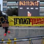 A person holding a placard reading “Sometimes dreams come true” sits beside a banner that says “Until the last hostage” at Hostages Square in Tel Aviv, Israel, on January 27, 2026. The gathering took place on the day the iconic countdown clock was turned off after marking 844 days since the October 7, 2023 Hamas attack. The moment followed the return of Israel’s last remaining hostage from Gaza, Ran Gvili, an off-duty police officer who was killed while fighting militants who had infiltrated Israel during the attack.